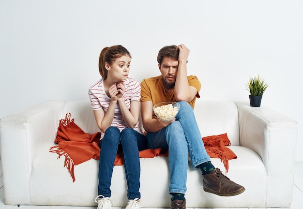 Casal no sofá pipoca assistindo tv dentro de casa homem mulher