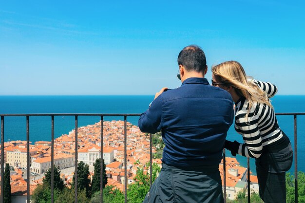 Casal olhando para a paisagem urbana de Piran no mar Adriático na Eslovênia