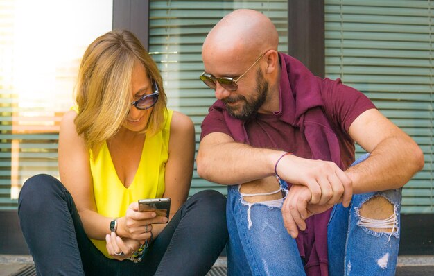 Foto casal olhando para o celular contra a janela