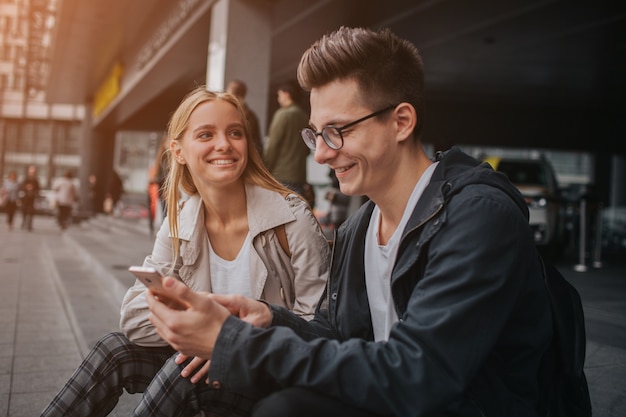 Casal ou amigos rindo engraçado e se divertindo com um telefone inteligente em uma rua da cidade grande.