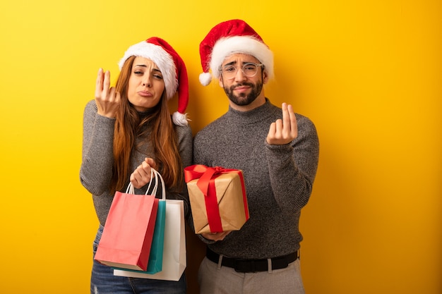 Casal ou amigos segurando presentes e sacolas de compras, fazendo um gesto de necessidade