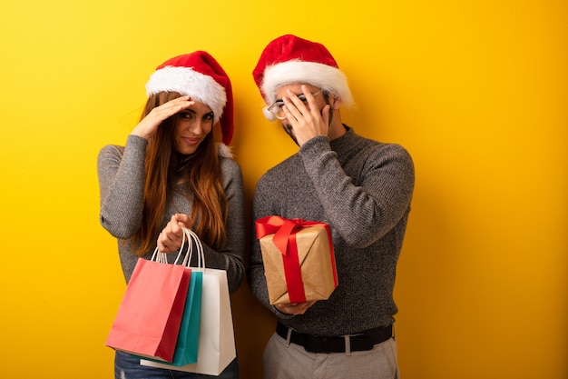 Casal ou amigos segurando presentes e sacos de compras envergonhados e rindo ao mesmo tempo