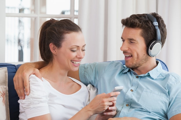 Casal ouvindo música com celular no sofá