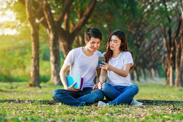 casal ouvindo música do celular com fone de ouvido no parque