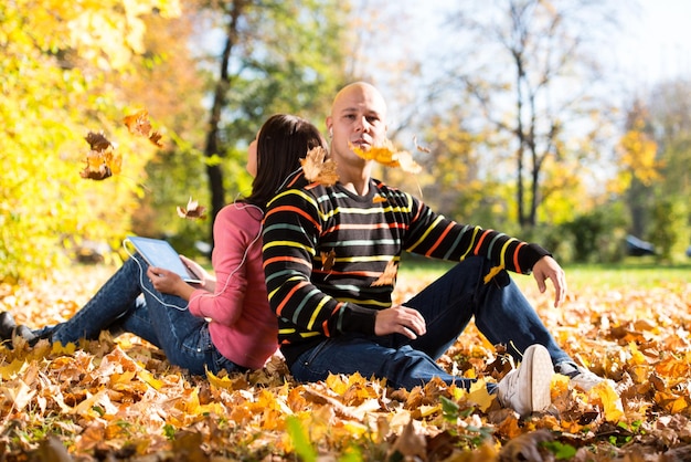 Foto casal ouvindo música nas folhas de outono