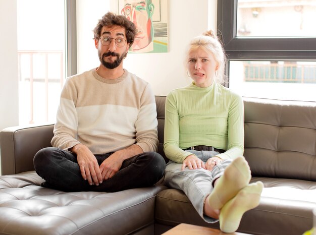 Casal parecendo perplexo e confuso, mordendo o lábio com um gesto nervoso, sem saber a resposta para o problema