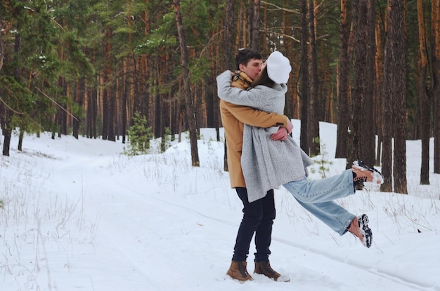 casal. parque nevado, floresta. Jovem mulher, homem de chapéu andando. pinheiros cobertos de neve. Inverno