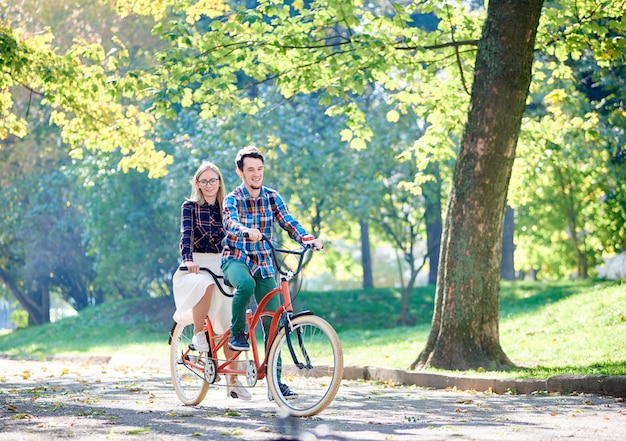 Casal pedalando juntos em uma bicicleta tandem