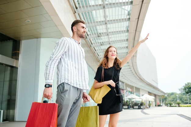 Casal pegando táxi depois de fazer compras