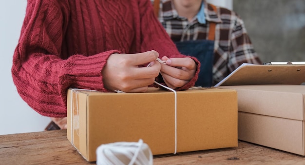 Casal pequeno empresário trabalhando com computador no local de trabalho Casal vendedor de negócios verifica o pedido do produto Embalagem de mercadorias para entrega ao cliente Venda on-line Ecommerce Conceito de remessa