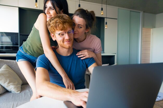 Foto casal poliamoroso em casa trabalhando no laptop