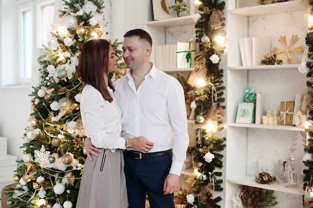 Casal posando ao lado da árvore de Natal