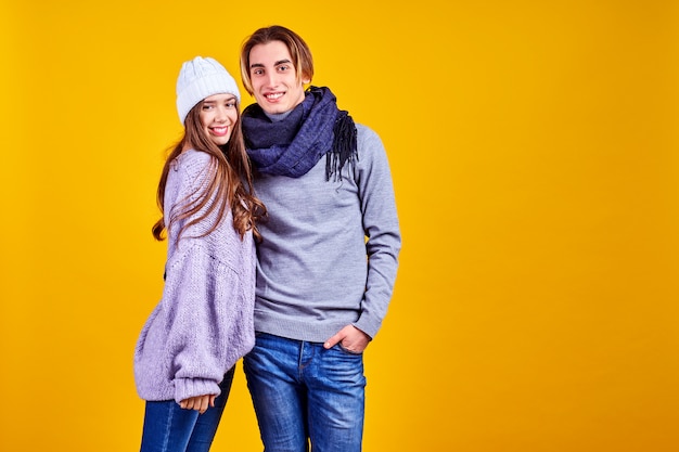 Casal posando em jeans tipo estilo de moda comercial na parede amarela