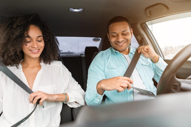 Casal praticando hábitos de condução seguros usando cintos de segurança no carro