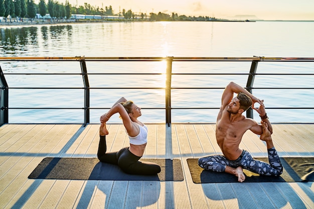 Casal praticando ioga juntos em exercícios matinais ao ar livre na natureza ao nascer do sol