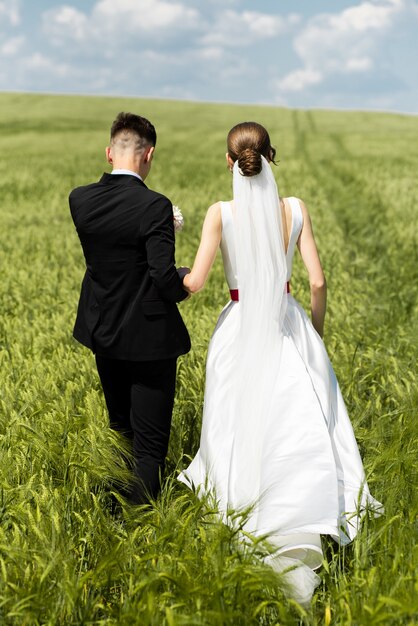 Casal recém-casado caminhando no dia do casamento ao ar livre no campo