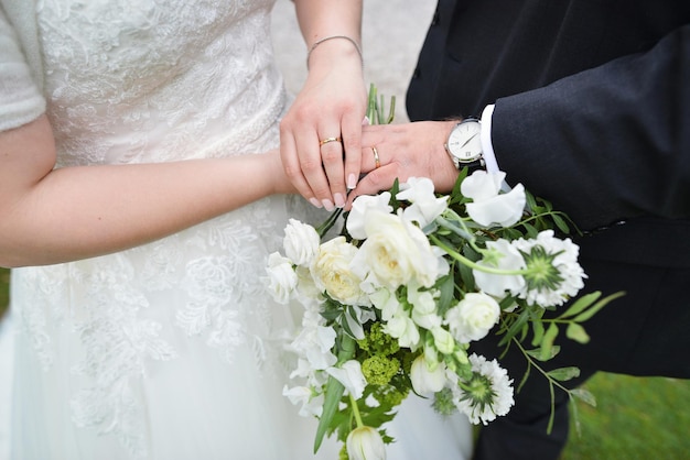 Casal recém-casado de mãos dadas e exibindo alianças de casamento buquê no altar na igreja