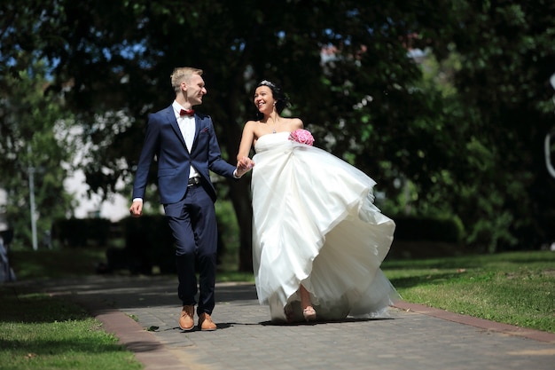 Casal recém-casado muito feliz caminhando no parque no dia do casamento