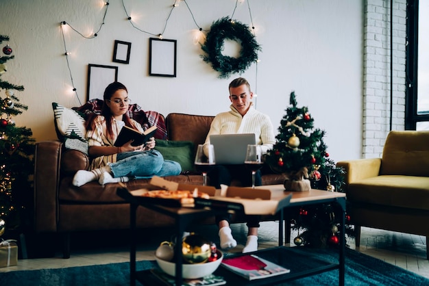 Casal relaxante com livro e laptop no Natal