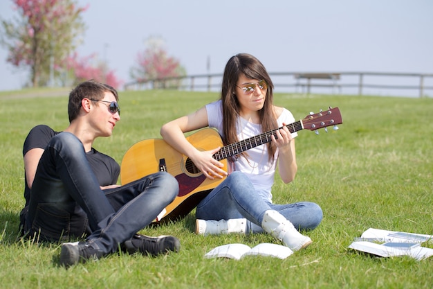 Casal relaxante e tocar guitarra ao ar livre