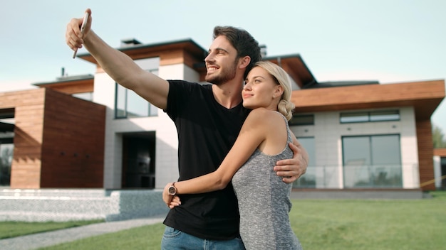 Casal rico se abraçando perto de apartamentos de luxo Selfie retrato de casal feliz