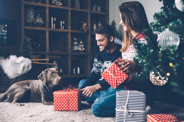 Casal rindo com presentes e cachorro