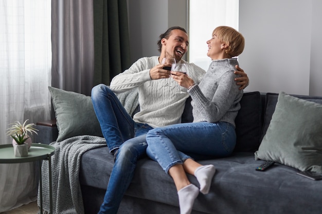 Casal rindo e bebendo vinho em casa