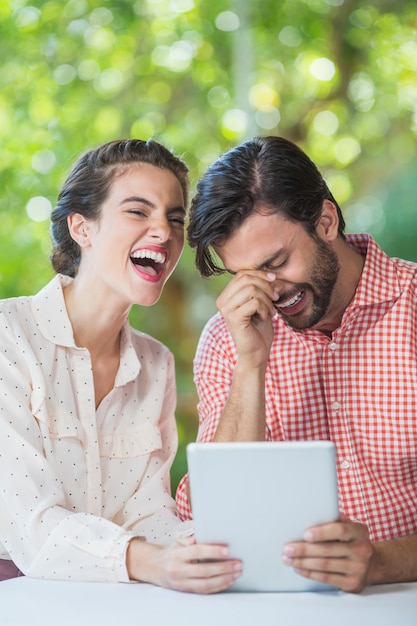 Casal rindo enquanto estiver usando tablet digital