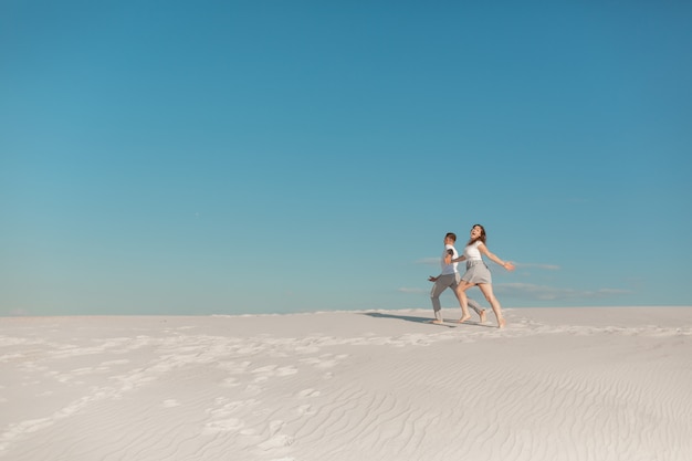 Casal romântico apaixonado correndo na areia branca no deserto