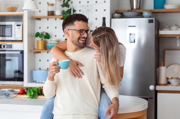 Casal romântico apaixonado passando tempo juntos na cozinha Jovem casal bonito tomando café na cozinha e aproveitando o tempo da manhã juntos