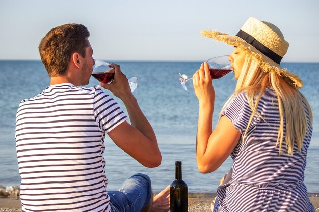 Casal romântico apreciando vinho à beira-mar