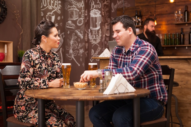 Casal romântico bebendo cerveja em um bar moderno e fazendo um brinde. Vibe legal.