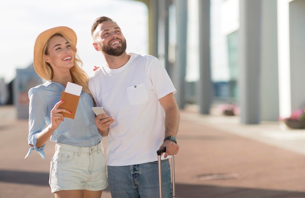 Foto casal romântico chegando no aeroporto e olhando de lado