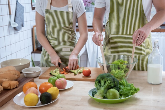 Casal romântico cozinhando na cozinha em casa. caucasiano jovem bonito e jovem atraente se divertindo juntos ao fazer salada. conceito de estilo de vida saudável.