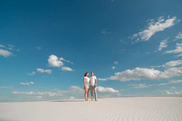 Casal romântico dançando no deserto de areia no céu azul