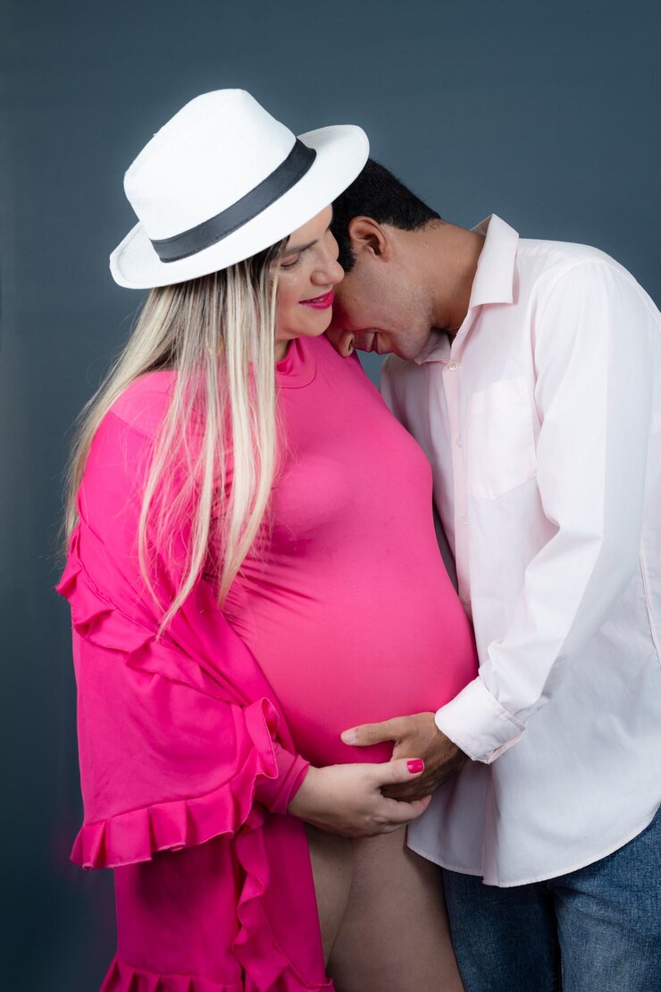 Foto casal romântico de marido e esposa grávida em chapéus posando em retrato de estúdio