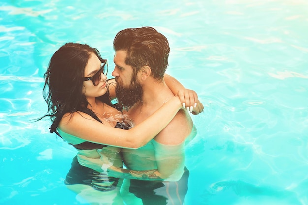 Casal romântico e sensual sozinho na piscina infinita sobre um lindo fundo de água azul