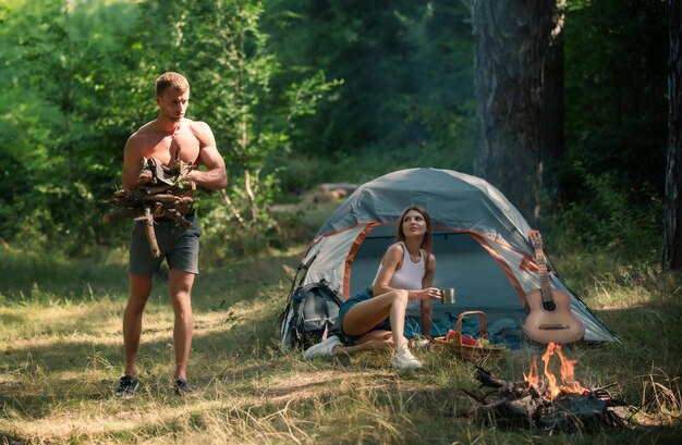 Casal romântico em acampamento aventura ao ar livre com amigos na natureza casal despreocupado perto da fogueira