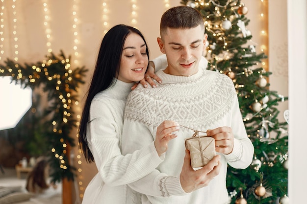 Casal romântico em pé perto da árvore de Natal e segurando uma caixa de presente