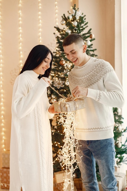 Casal romântico em pé perto da árvore de Natal e segurando uma caixa de presente