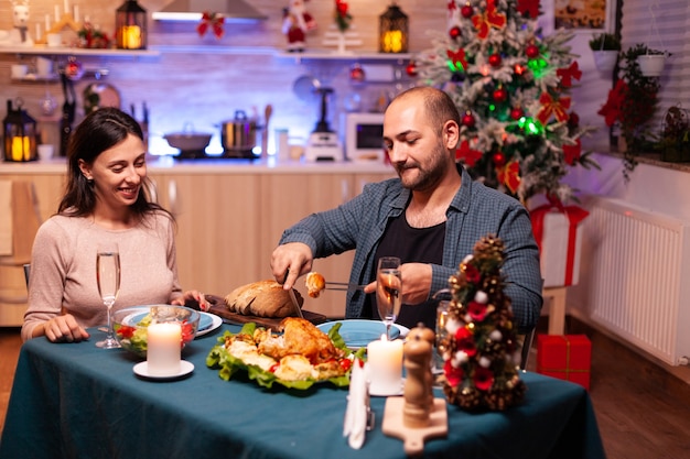 Casal romântico feliz jantando no Natal, sentado à mesa de jantar