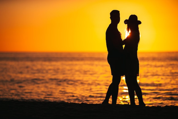 Casal romântico na praia ao pôr do sol colorido no fundo