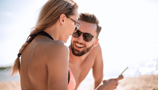 Casal romântico navegando suas fotos na praia