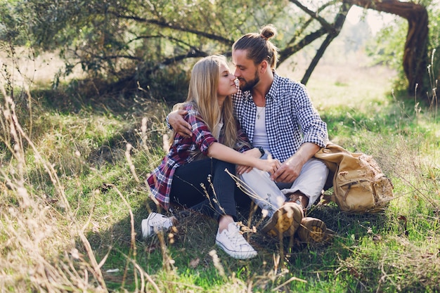 Casal romântico se abraçando e sentado no parque, vestindo camisa. jovem com seu namorado bonito com barba, aproveitando o dia de sol.