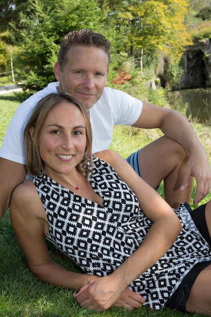 Casal romântico sorrindo e abraçando no parque à beira do lago em dia ensolarado