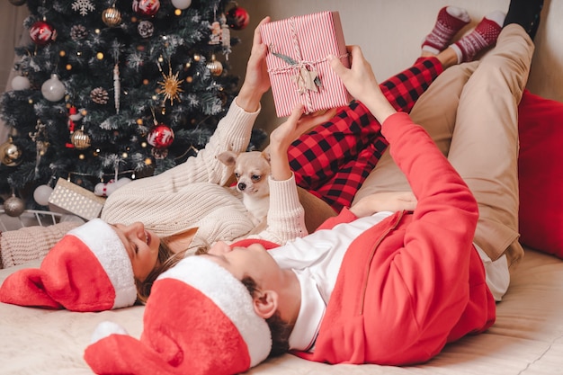 Casal romântico trocando presentes perto da árvore de natal decorada