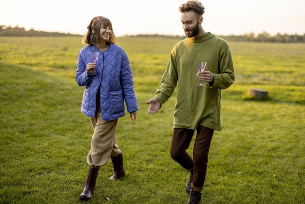 Casal sai juntos andando no campo verde ao pôr do sol