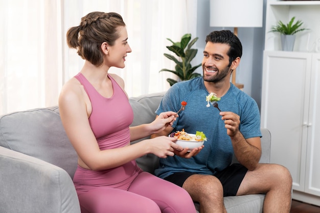 Casal saudável, desportivo e vegetariano em roupas desportivas com vegano em casa alegre
