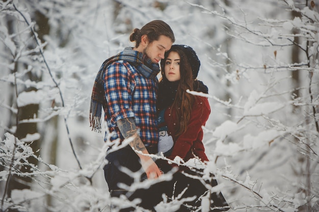 Casal se abraçando na floresta de inverno