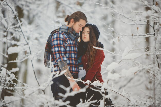 Casal se abraçando na floresta de inverno